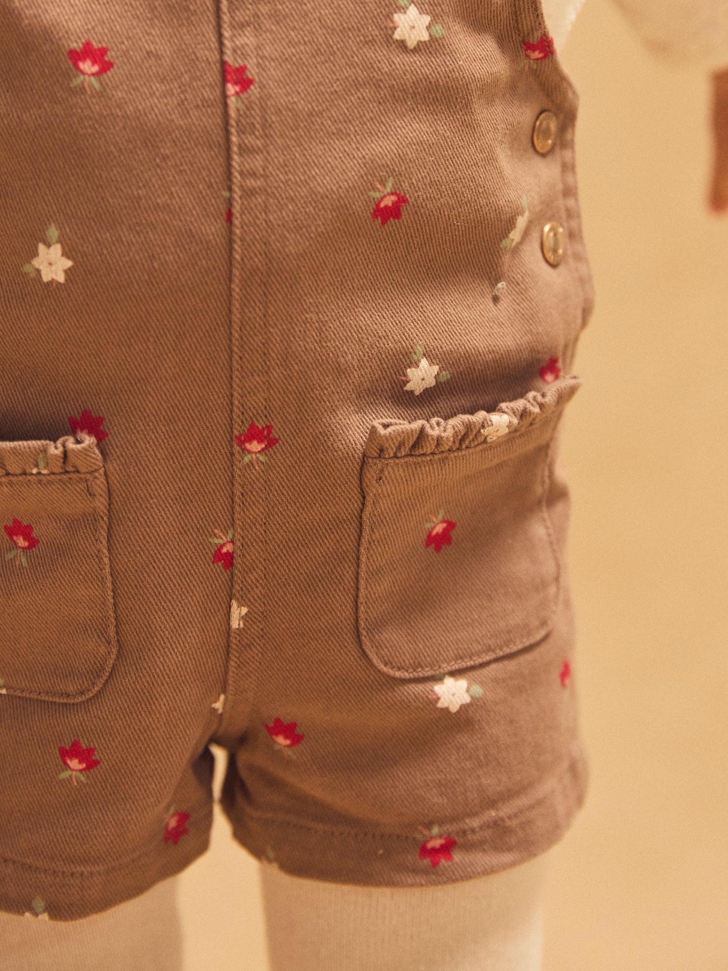 Kurze braune Latzhose mit Blumenmuster für Mädchen