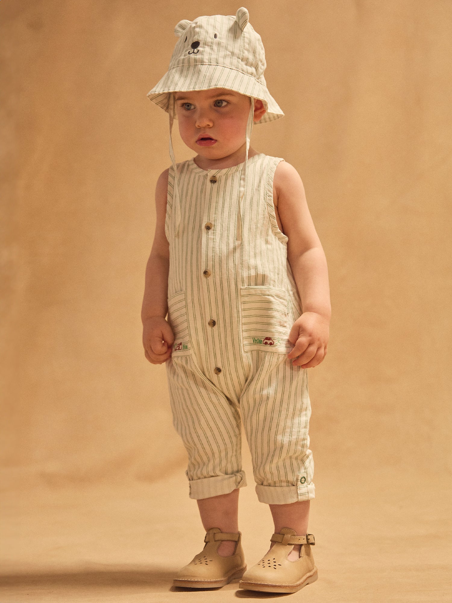 Weiße Latzhose mit grünen Streifen für Baby Junge.